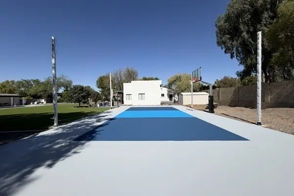 Light grey pad with two blue color zones coated, light poles set and a hoop at the far end