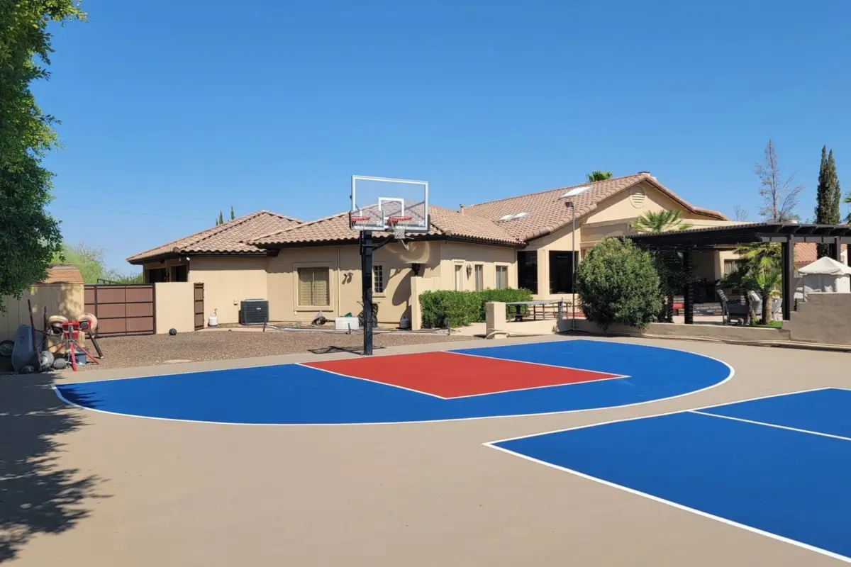 Backyard half court with a red key and blue lane, an in-ground hoop and a Phoenix house behind