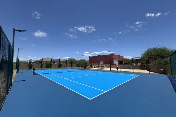 Fenced two-tone blue pickleball court with desert and mountains behind