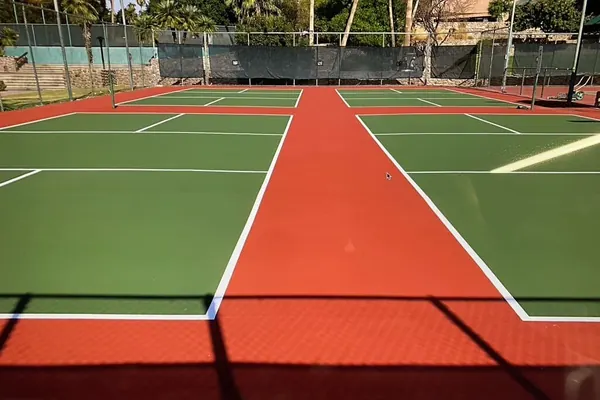 Red and green multi-court pickleball complex with palm trees